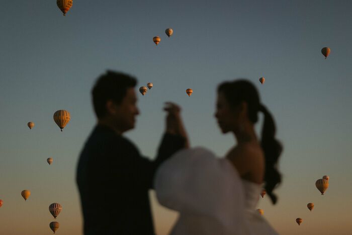 Silhouetted couple at a destination wedding with hot air balloons in the background.