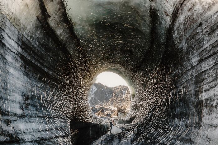 A couple stands inside a stunning ice cave, showcasing top destination wedding photography of 2024.