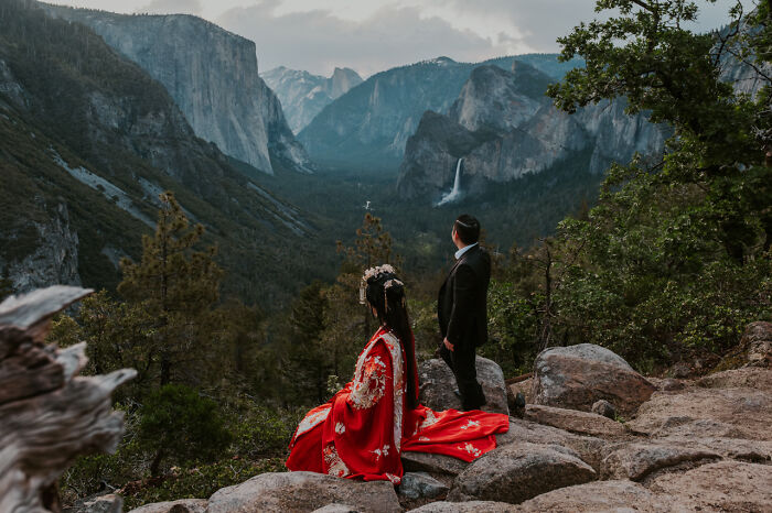 Couple in elegant attire at cliff overlooking a breathtaking valley, epitomizing destination wedding photography.