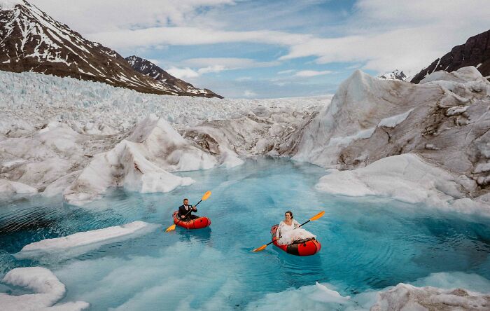 Couple on a glacier lake in red kayaks, highlighting top destination wedding and couple photos of 2024.