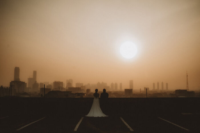 Couple silhouetted against a city skyline at sunset, showcasing top destination wedding photography of 2024.