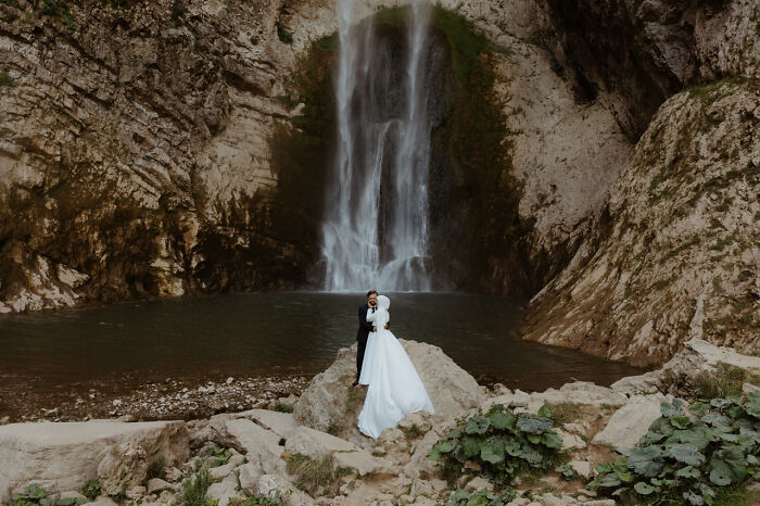 Couple in wedding attire posing by a waterfall, showcasing the best destination wedding photo of 2024.