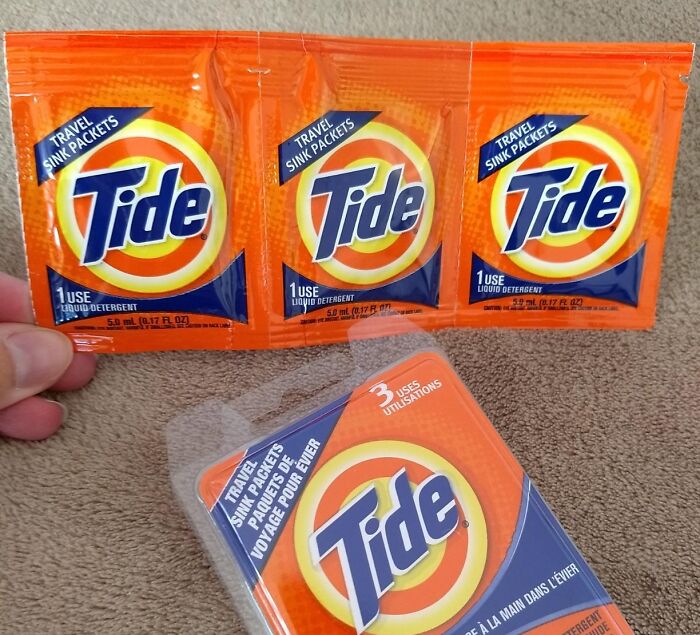 Mini Tide travel packets on a brown fabric, ideal for minimalist packing in carry-on luggage.