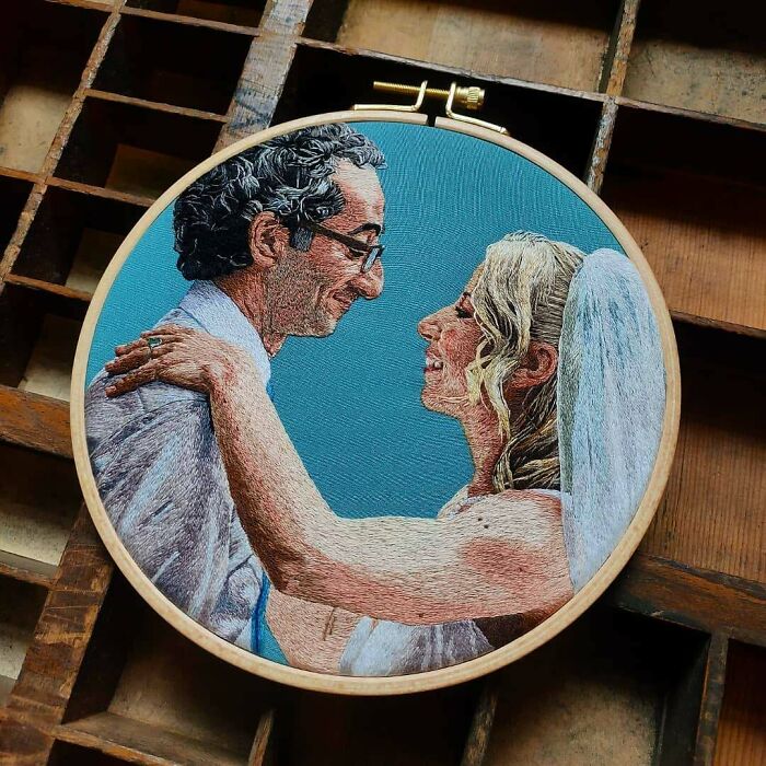 Creative embroidery art depicting a bride and groom embracing, showcasing detailed needlework on a blue background.