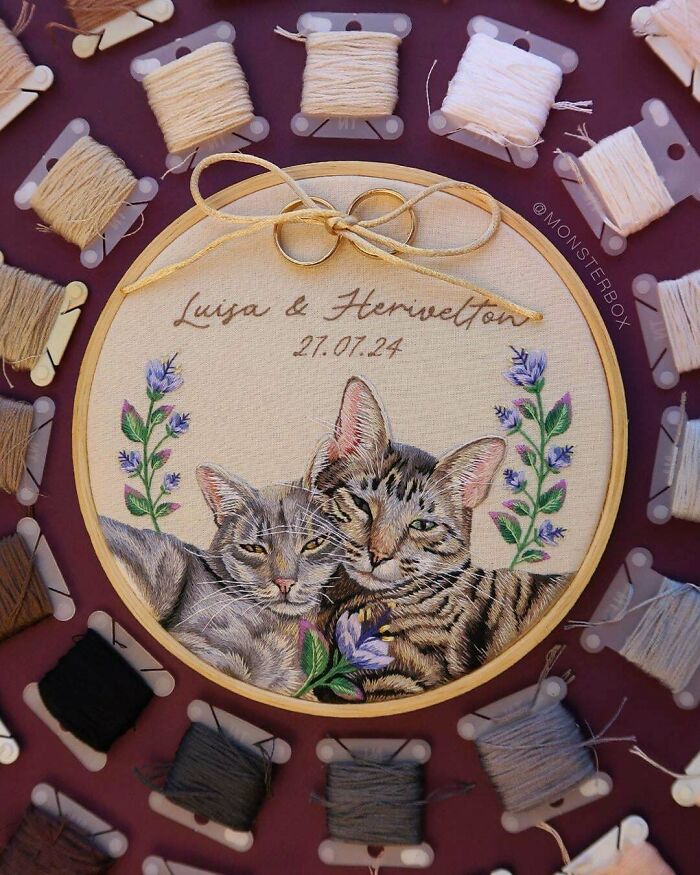 Creative embroidery of two cats surrounded by colorful threads, showcasing intricate stitching and design.