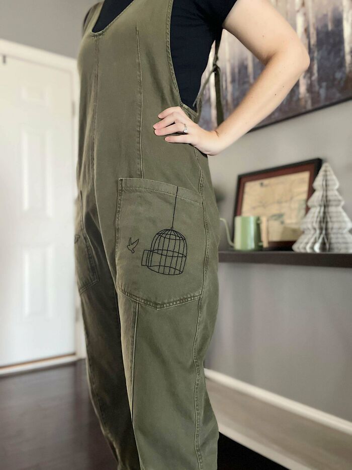 Creative embroidery on olive overalls featuring a bird cage design.