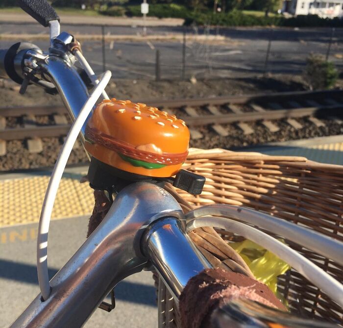 Burger-shaped bicycle bell adding goofiness to a sunny ride by the train tracks.