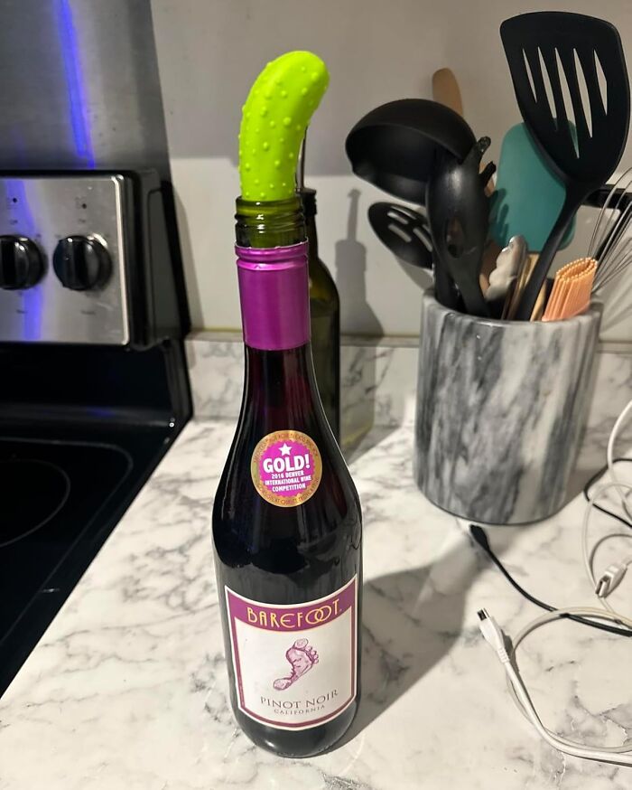 A bottle of wine humorously sealed with a green vegetable, showcasing unexpected goofiness in a kitchen setting.