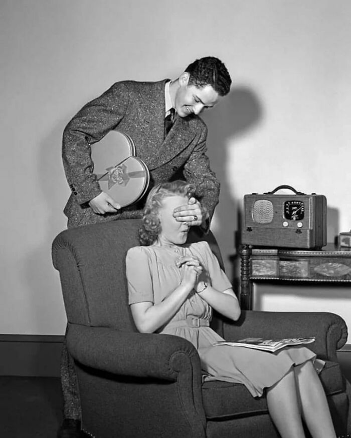 Teen Boy With Hand Over Girl Eyes Surprising Her With Box Of Valentine’s Day Candy, 1940s