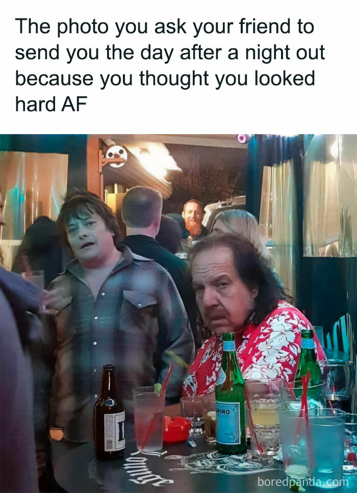 Meme of the day: The image shows a man with a tired, unimpressed expression sitting at a bar table cluttered with drinks. Another person with a disheveled appearance stands in the background. The text above the image reads, "The photo you ask your friend to send you the day after a night out because you thought you looked hard AF." The meme humorously captures the contrast between how one feels they look during a night out versus the reality captured in a photo.