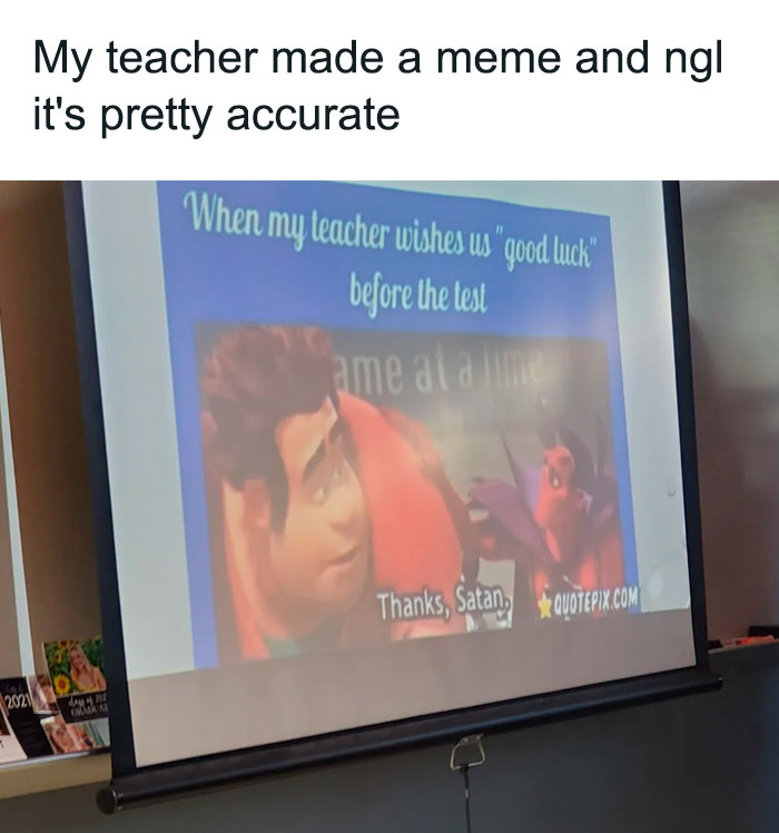 A teacher meme showing a projected image on a classroom screen. The image features characters from an animated movie with text reading, "When my teacher wishes us 'good luck' before the test," and a character replying sarcastically, "Thanks, Satan." The caption above the meme reads, "My teacher made a meme and ngl it's pretty accurate," humorously highlighting the common student sentiment of feeling doomed before a difficult test.