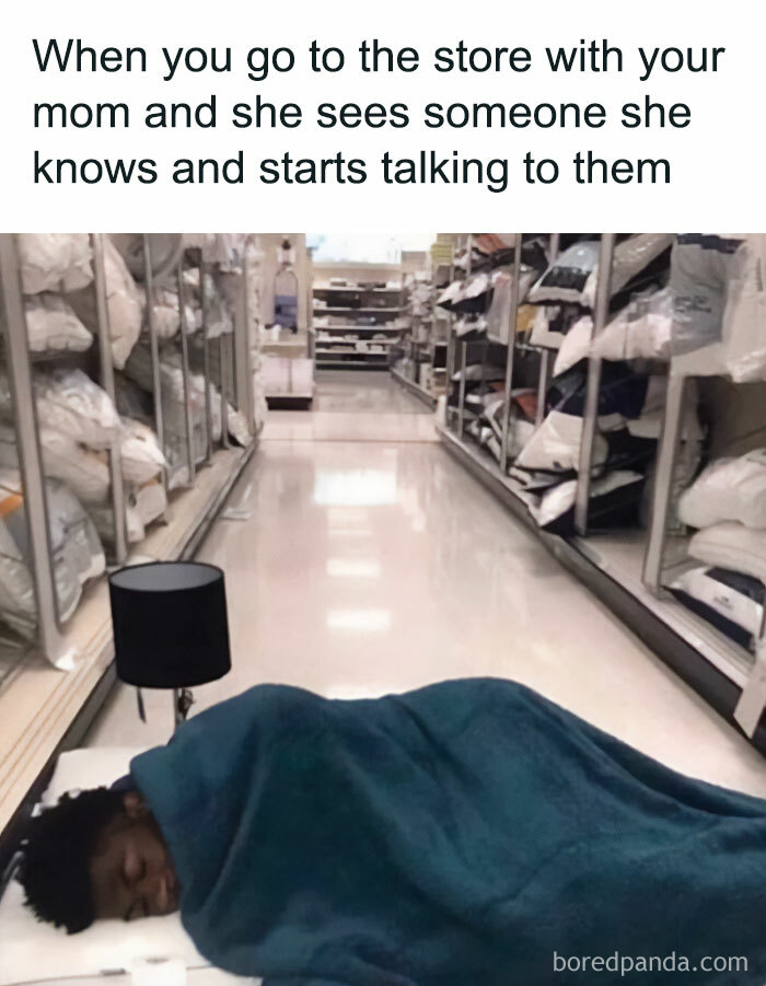 A Waiting meme featuring a person lying on a store aisle floor, covered with a blanket and a small lamp beside them, as if they are preparing to sleep. The text above reads, "When you go to the store with your mom and she sees someone she knows and starts talking to them," humorously capturing the feeling of boredom and endless waiting when a parent unexpectedly stops to chat during a shopping trip.