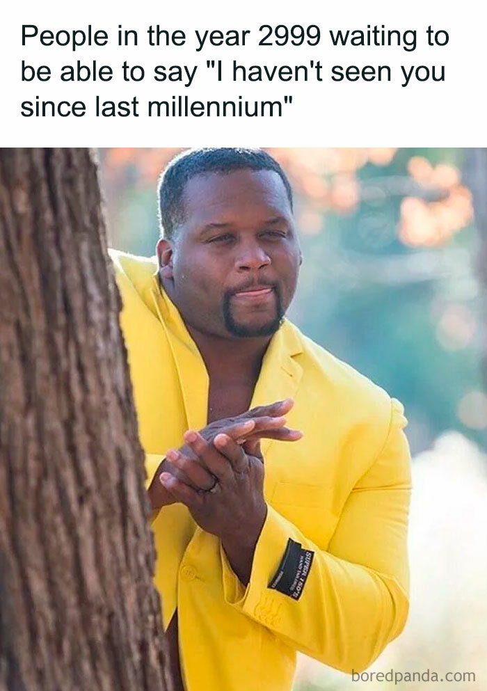 A Waiting meme showing a man in a bright yellow suit standing behind a tree, rubbing his hands together and looking eager. The text above reads, "People in the year 2999 waiting to be able to say 'I haven't seen you since last millennium,'" humorously depicting the anticipation of someone waiting for an opportunity to use this phrase.