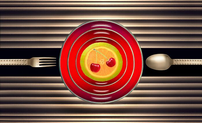 Colorful fruit on a red plate with a fork and spoon, showcasing creative advertising photography.