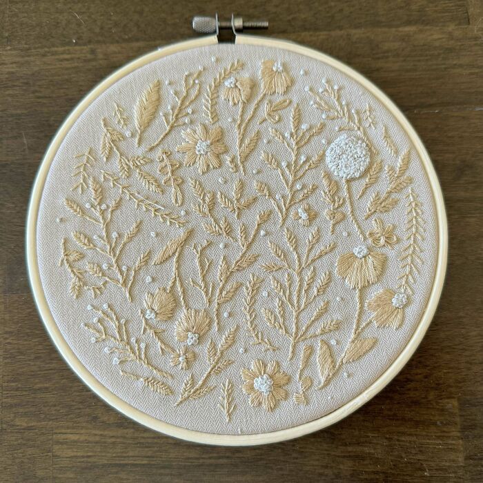 Creative embroidery on hoop featuring detailed floral patterns in beige and white thread.