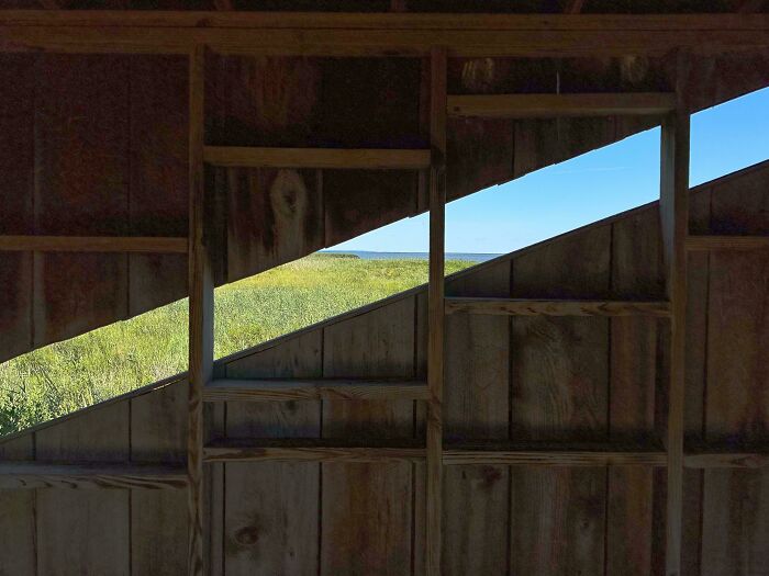 Este refugio de vida silvestre tiene ventanas diagonales en su puesto de observación para permitir que personas con diferentes alturas y necesidades de observación puedan ver aves y vida silvestre en la bahía cercana.