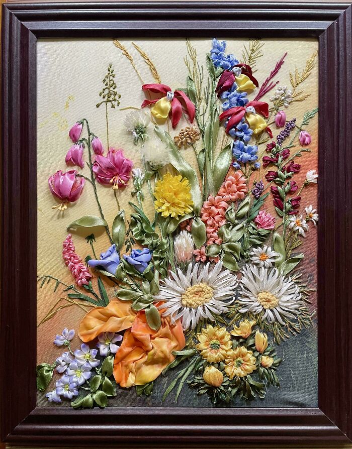 Creative embroidery art featuring vibrant, detailed floral designs in a wooden frame.