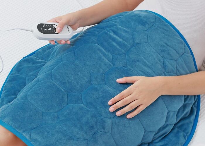 Stress Got Your Muscles Feeling Like They've Been Through A Wrestling Match? This Weighted Heating Pad Will Give Them The Warm Hug