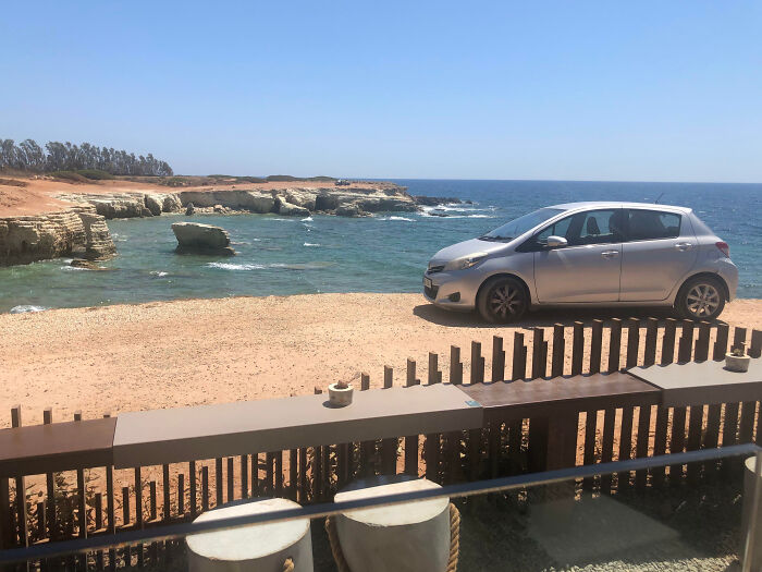 Tourists In Cyprus Parked Their Car In Front Of Outdoor Seating At A Restaurant, Blocking The View Of The Ocean