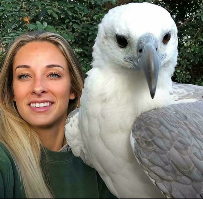 Woman smiling next to a large bird, showcasing the concept of absolute units in nature.