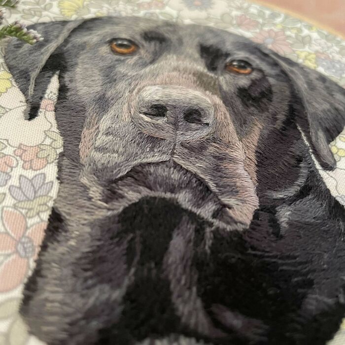 Creative embroidery of a black dog, showcasing detailed artistic needlework on a floral background.