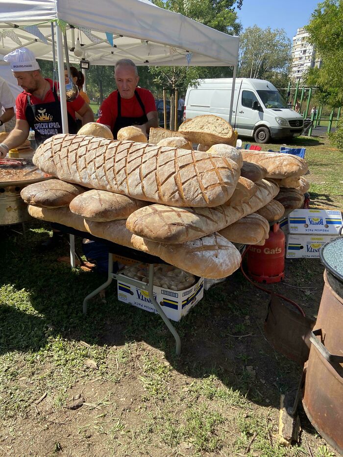 Massive loaves of bread displayed on a table at an outdoor market, exemplifying absolute-units-things.