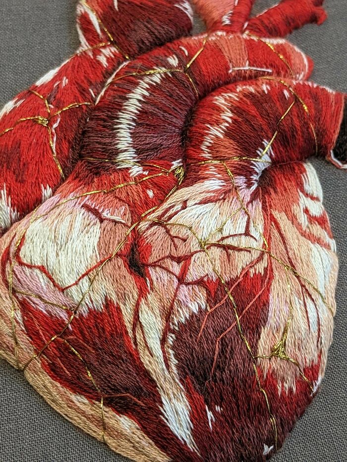 Embroidery art depicting an anatomical heart with intricate stitching and vibrant red threads.