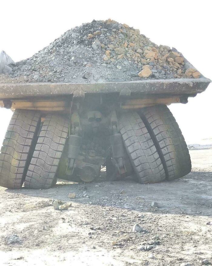 Overloaded dump truck with a collapsed axle, illustrating an unfortunate and costly incident.