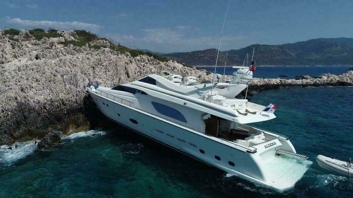 Luxury yacht stranded on rocky coastline, highlighting an unfortunate and costly incident.