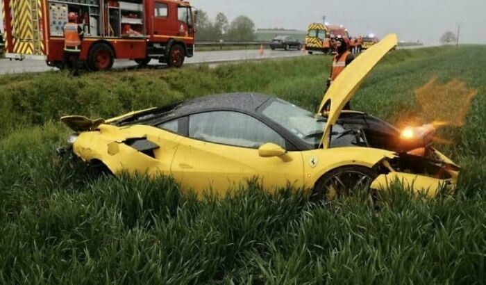 Yellow sports car accident in a grassy field, looking expensive with probable high repair costs.