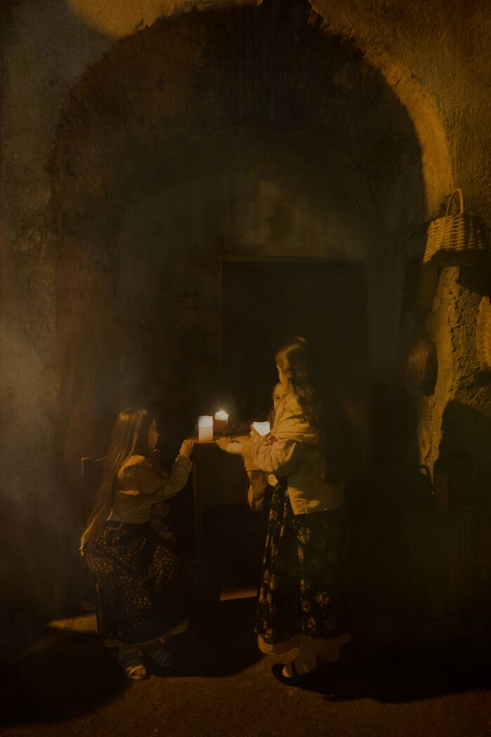 Children illuminated by candlelight in a rustic setting, capturing a winning shot from Tokyo International Foto Awards 2023.