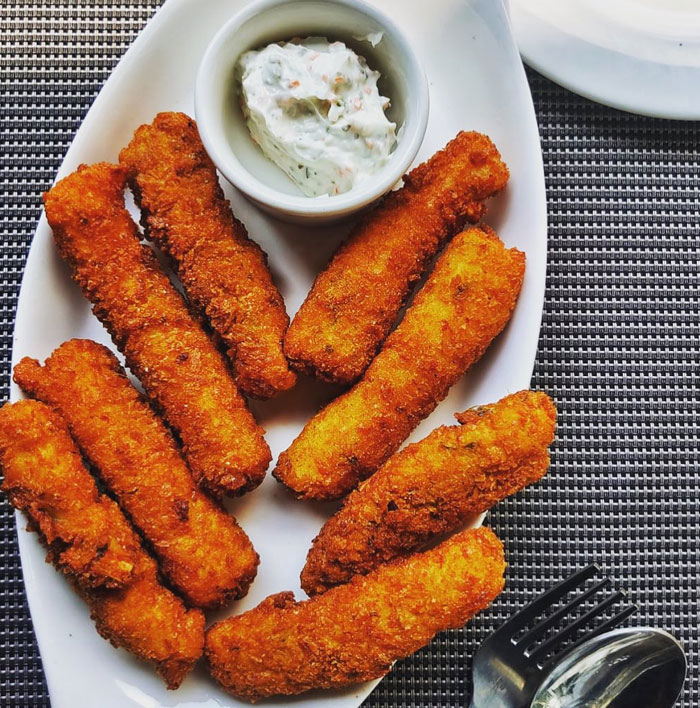 A Lunch idea featuring crispy golden fish fingers arranged on a white plate with a side of creamy dipping sauce, ready to serve.