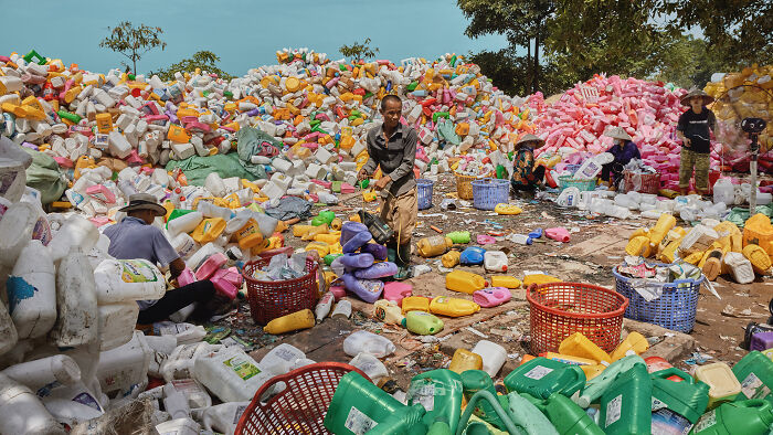 People sorting colorful plastic containers at a recycling site, showcasing future photography trends.