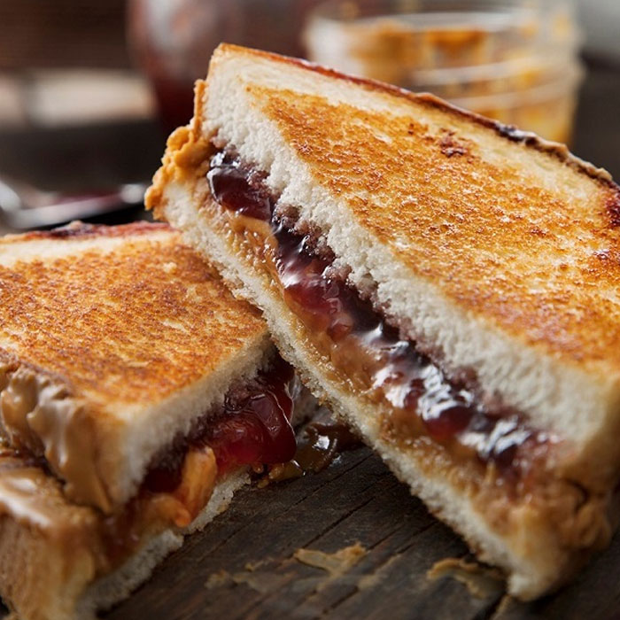 A Lunch idea featuring a grilled peanut butter and jelly sandwich with golden toasted bread, oozing with creamy peanut butter and sweet jelly.