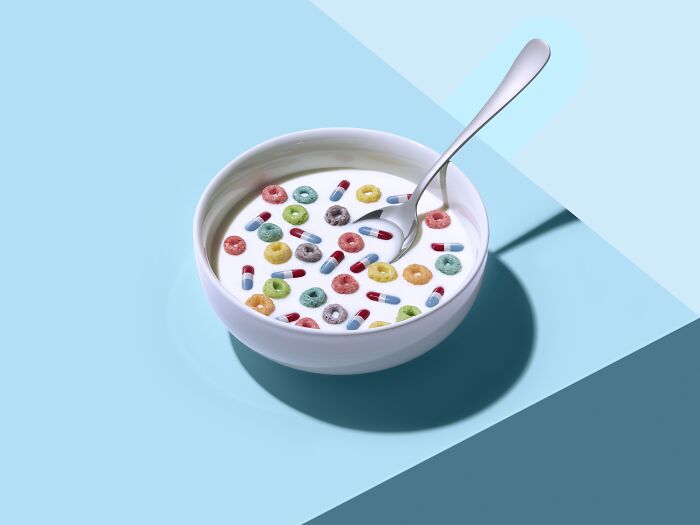 Bowl of cereal with colorful pills, highlighting creativity in advertising photography from Budapest Foto Awards 2023.