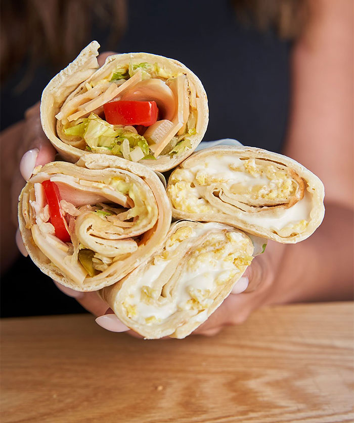 A Lunch idea featuring handheld lavash wraps filled with a variety of ingredients including lettuce, tomato, cheese, and scrambled eggs.