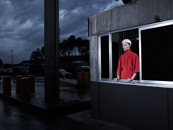 Person in red coat standing by a window at dusk, part of winning photographs from Tokyo International Foto Awards 2023.