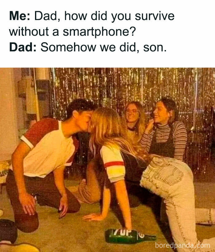 A Dad meme showing a humorous conversation between a child and their father about life before smartphones. The text reads: "Me: Dad, how did you survive without a smartphone? Dad: Somehow we did, son." Below, there is an image of a vintage-looking party scene with a group of teenagers playing "spin the bottle." A boy and girl are leaning in for a kiss, while others watch with smiles, capturing a classic moment from a time when entertainment was simpler. The meme humorously suggests that socializing without technology involved creative and engaging activities like party games.