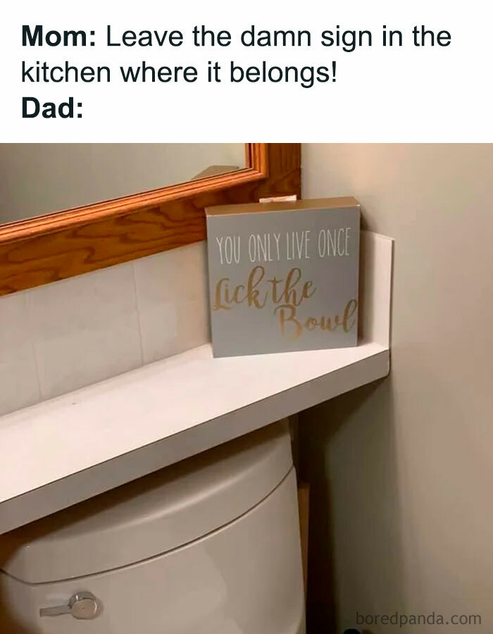 A Dad meme featuring a humorous scenario where a sign that reads "You Only Live Once, Lick the Bowl" is placed on a bathroom shelf above a toilet. The text above the image says, "Mom: Leave the damn sign in the kitchen where it belongs!" followed by "Dad:" implying that the dad has mischievously relocated the sign to the bathroom, creating a playful and ironic context.