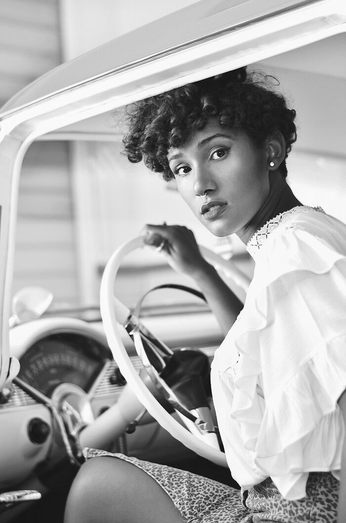 Woman in vintage car, black and white, part of Budapest International Foto Awards advertising collection 2023.