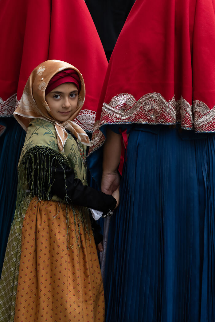 Child in traditional attire standing among people in colorful robes, highlighting future of photography.