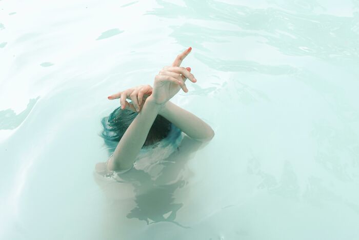 Person submerged in water with only their hands above the surface.