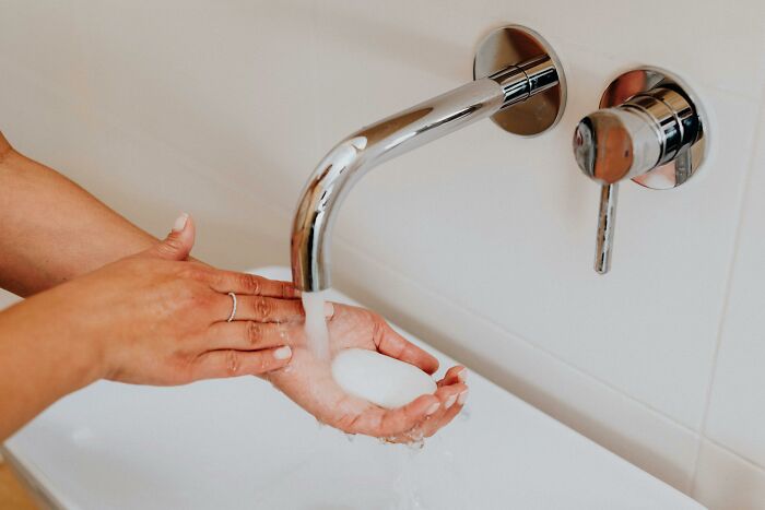 Close-up of hands under a running water faucet, soap lathering; concept related to hilariously inaccurate fact.