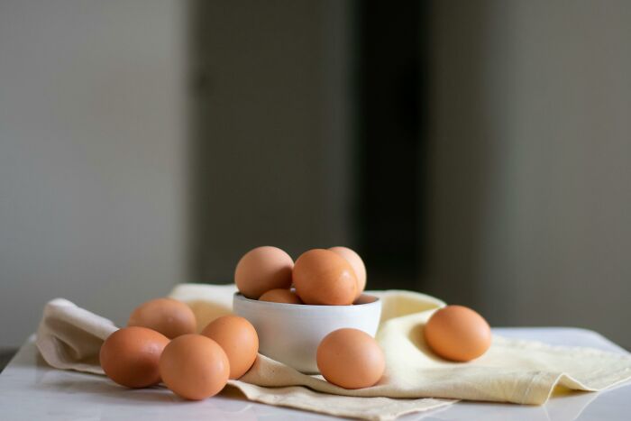 A bowl full of brown eggs placed on a beige cloth, illustrating a hilariously inaccurate fact about eggs.