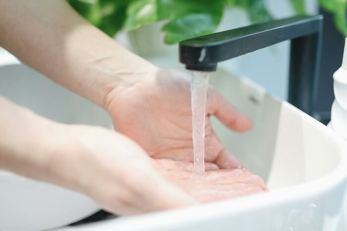 Hands under running water from a faucet.