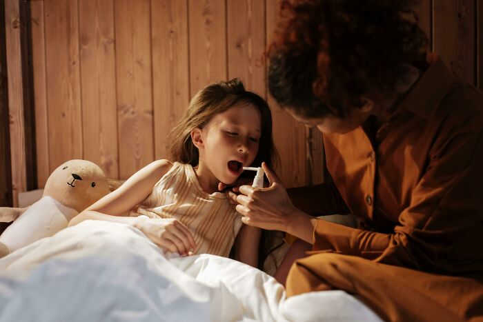 Child in bed showing thermometer to woman.