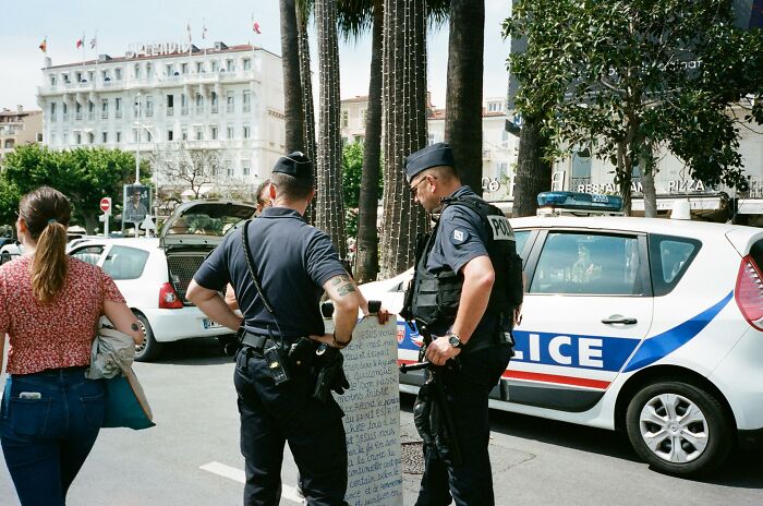 Police officers reading a sign on a busy street scene.