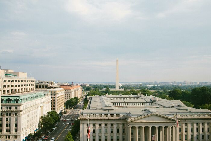 Aerial view of Washington D.C. skyline with the Washington Monument under a cloudy sky.