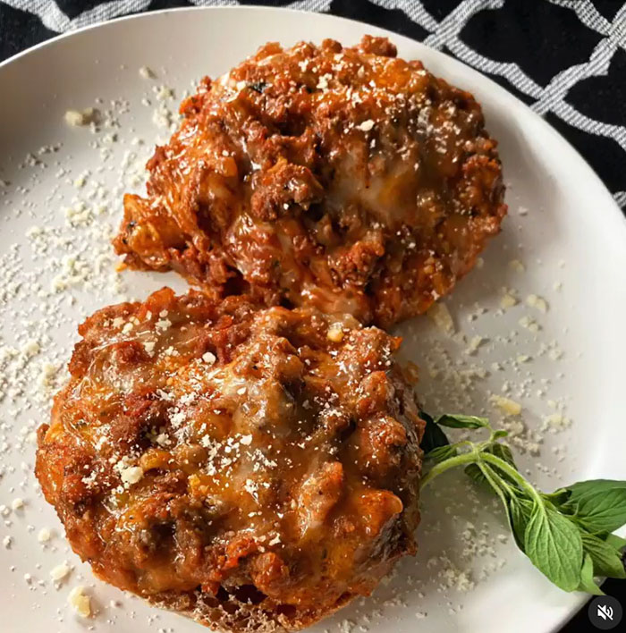 A savory lunch idea featuring two portions of baked stuffed mushrooms topped with a rich meat sauce and melted cheese, garnished with grated parmesan and fresh herbs, served on a white plate.