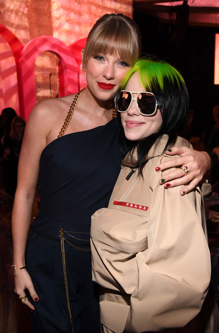 Taylor Swift in a navy outfit standing beside Billie Eilish, who is wearing a beige Prada jacket and large sunglasses. How tall is Taylor Swift?